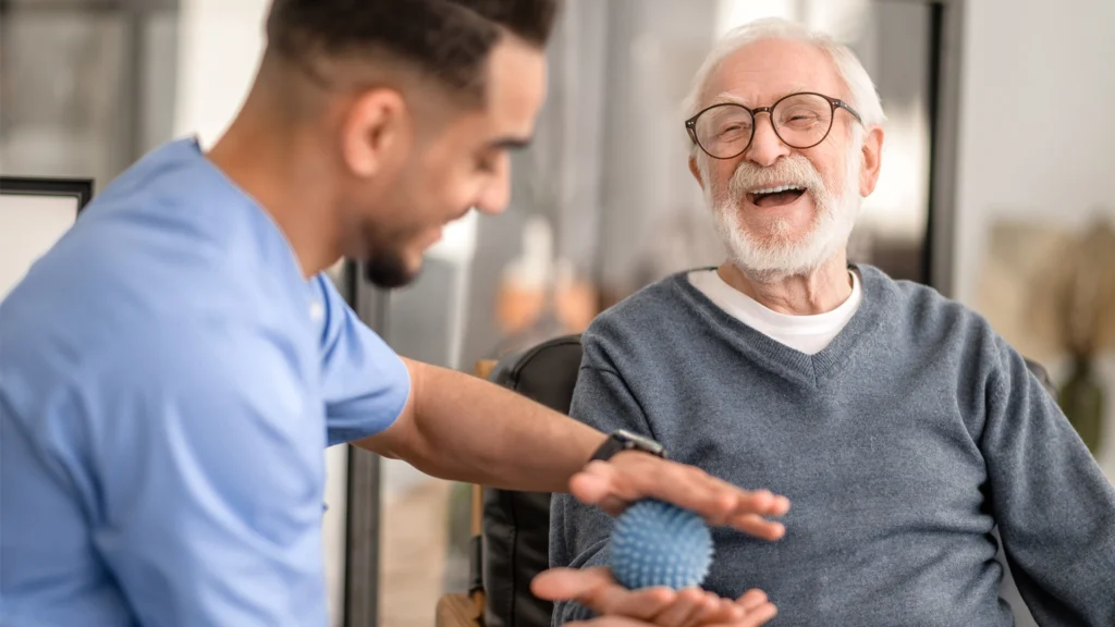 Elderly man enjoying hand exercises with a home health aide