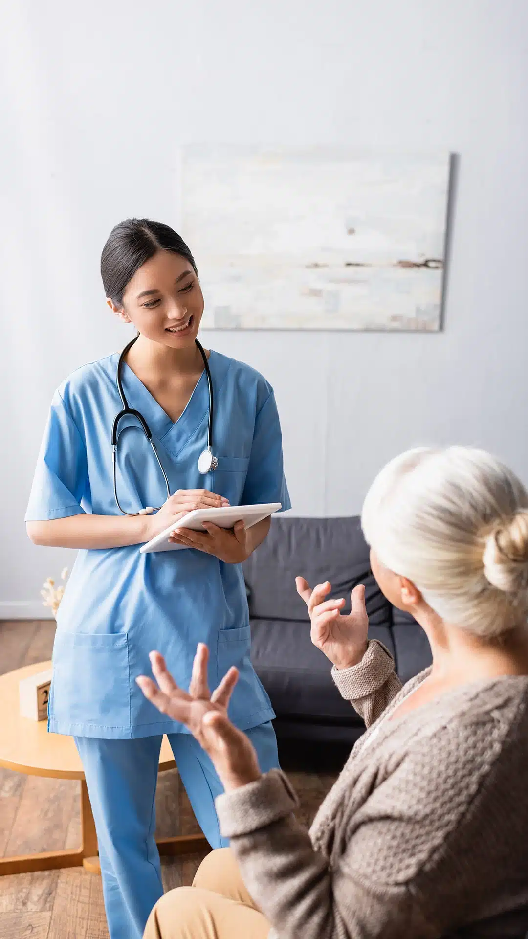 Skilled nurse speaking with a senior and assisting her with a health condition at home