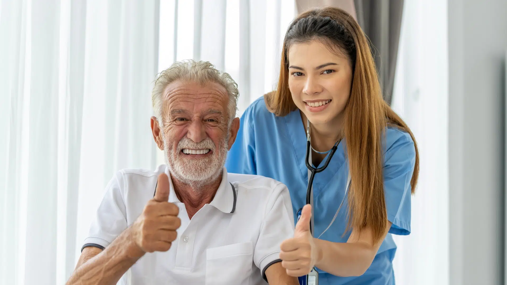 Home health nurse and senior holding their thumbs up
