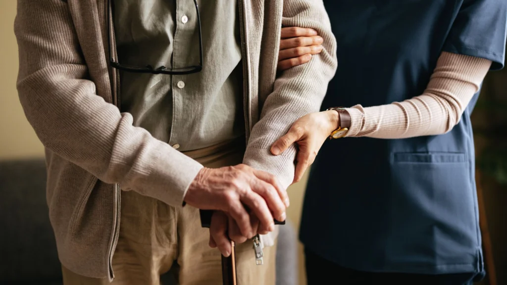 Caregiver supporting an elderly person holding a walking stick in Greenacres, FL
